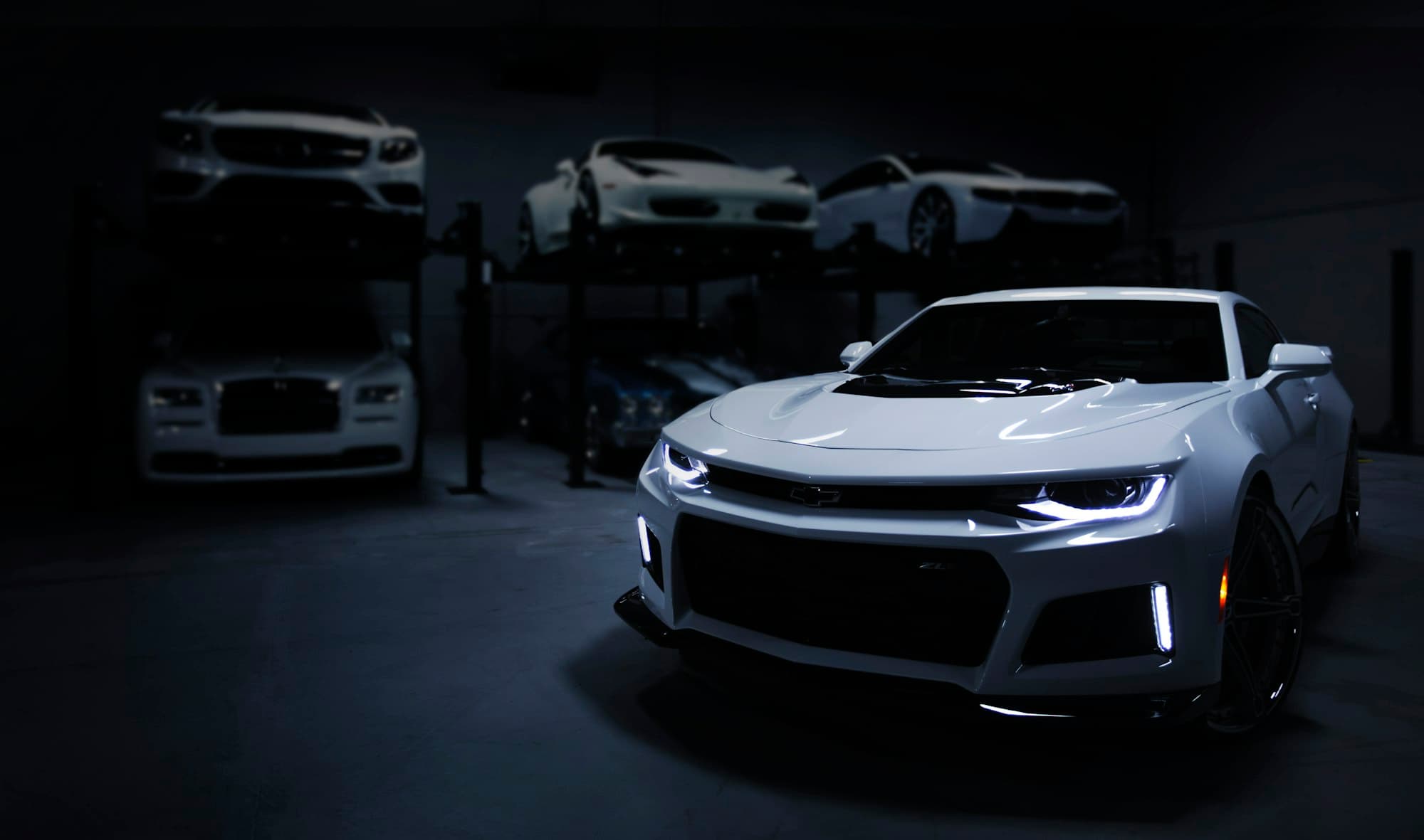 Performance cars in a darkened workshop, photographed for Carboratory