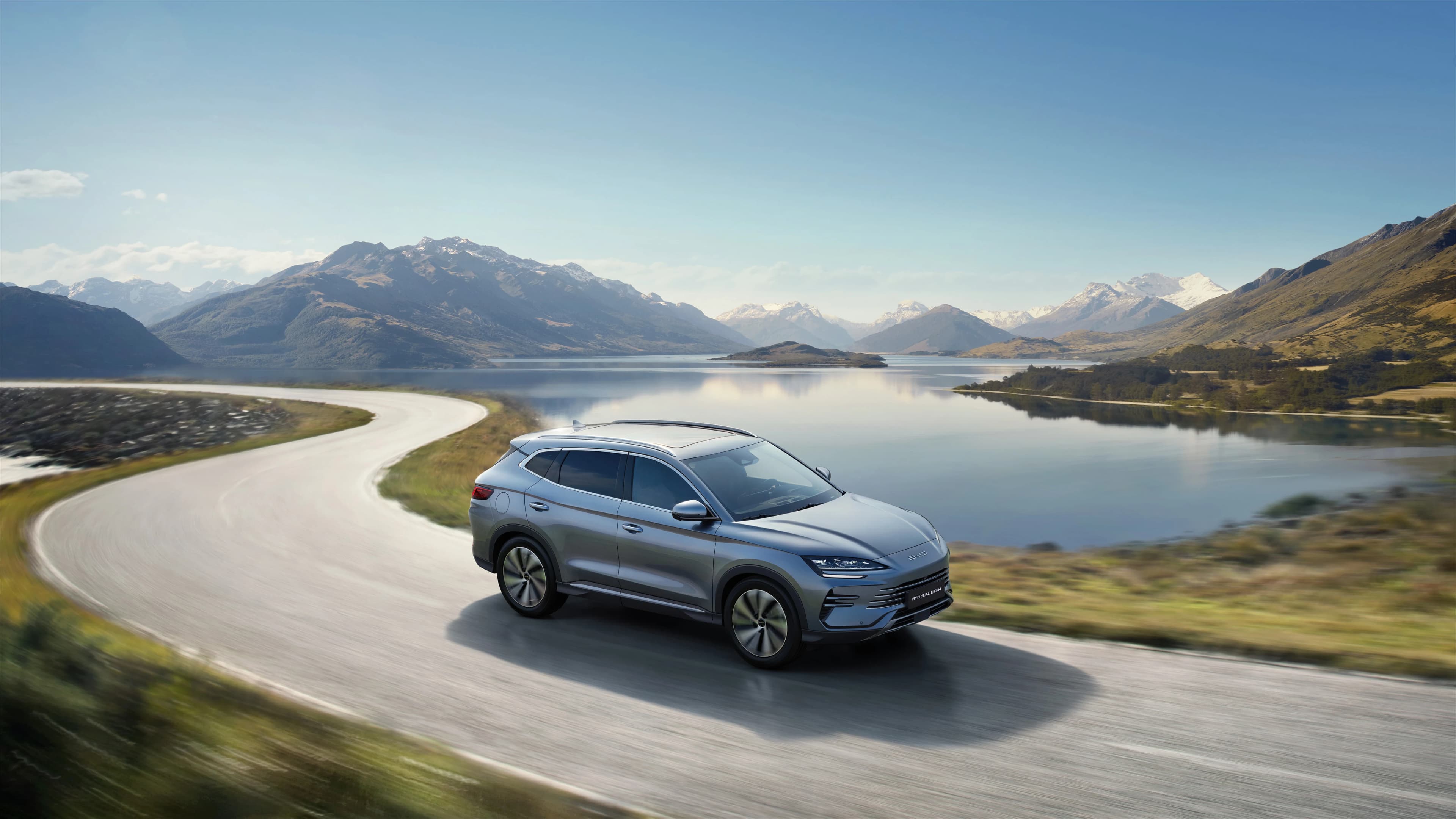 Ein BYD Seal U DM-i auf einer Straße an einem See und vor Bergen