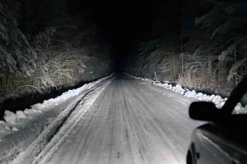 A Toyota Corolla using full beam and auxiliary lights on a dark winter road