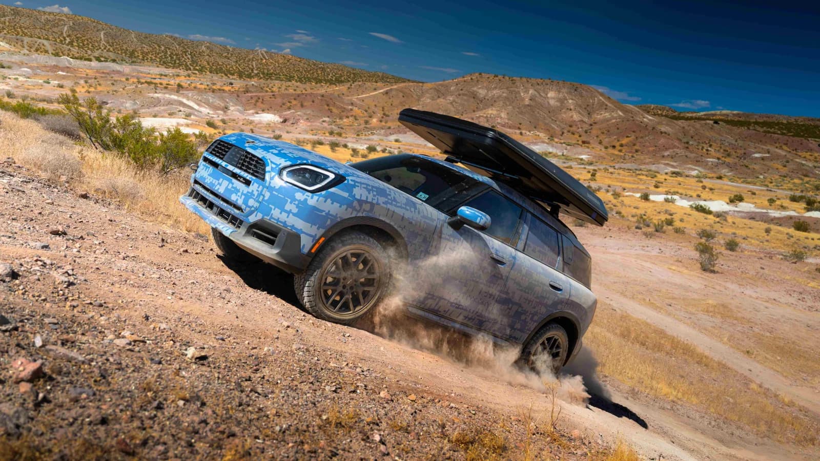 Camouflaged MINI Countryman prototype climbing a steep dirt track during Rebelle Rally preparation