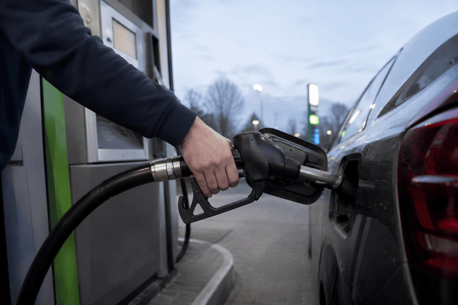Un conductor que abastece un coche en una gasolinera
