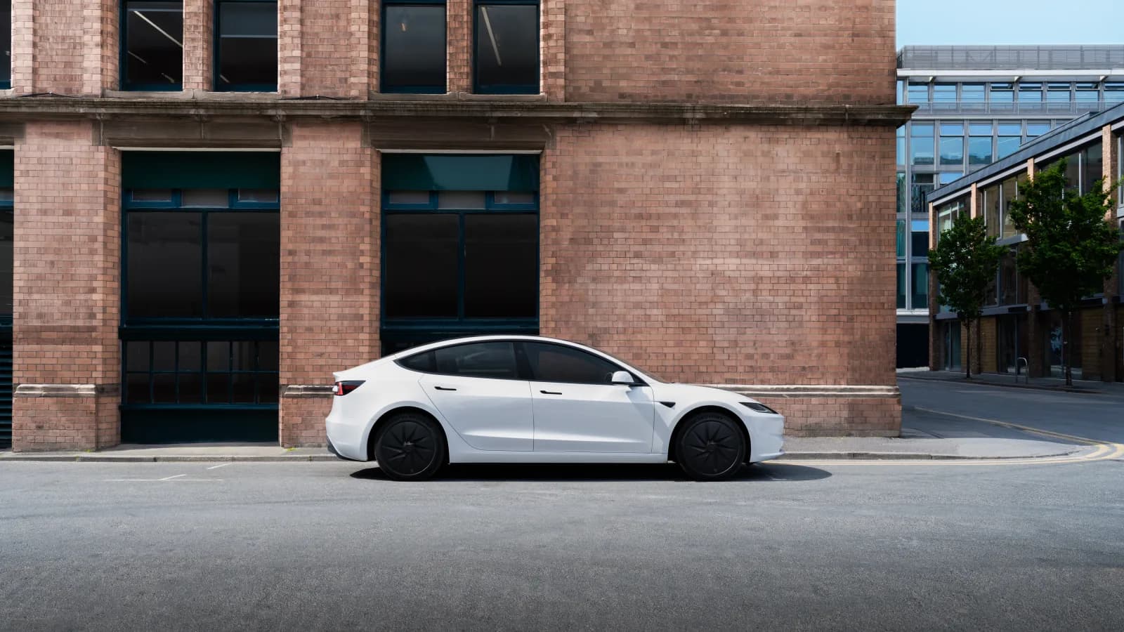 Tesla Model 3 alb văzut din lateral pe o stradă urbană