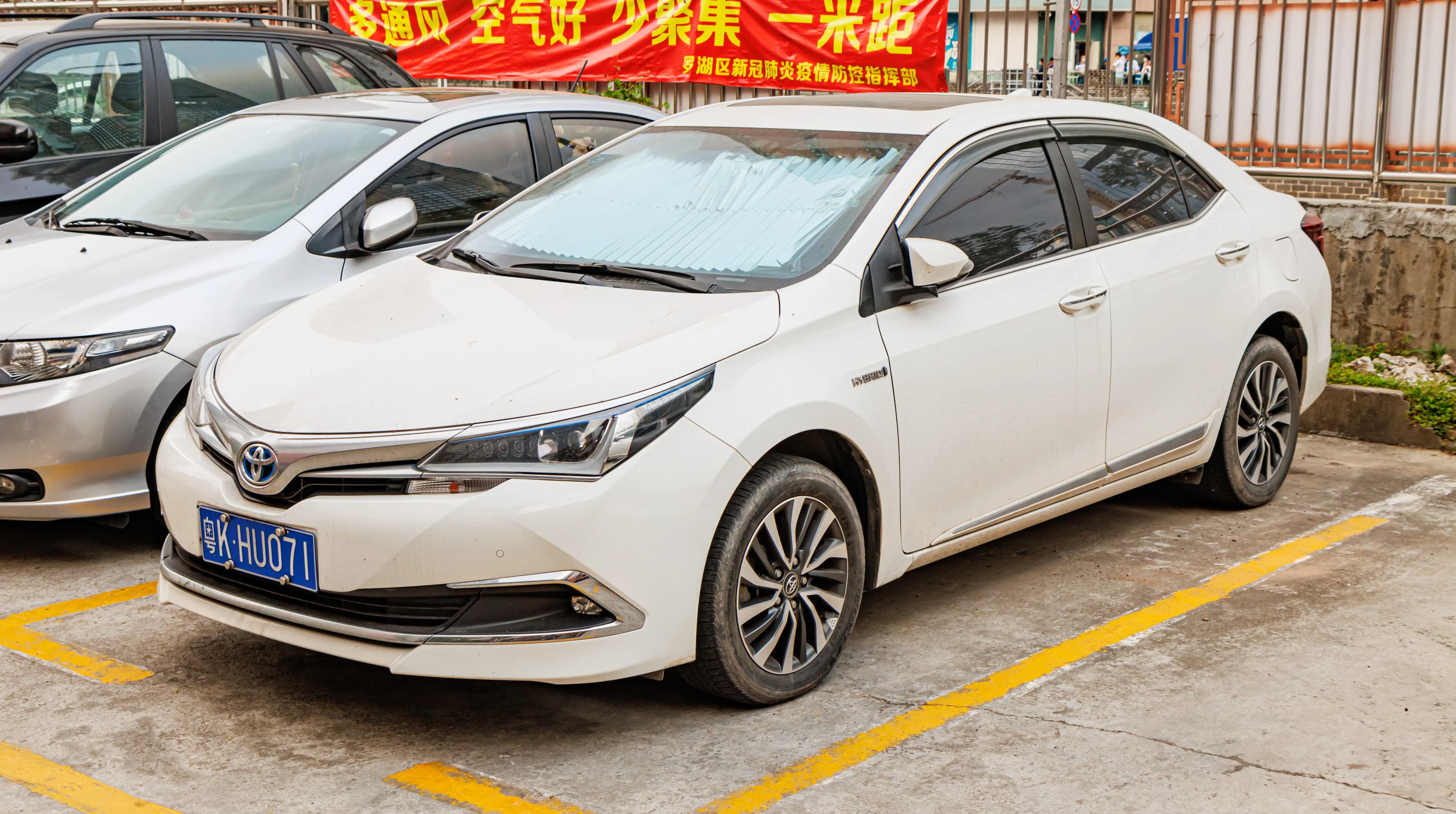 Toyota Corolla Hybrid blanche photographiée sur un parking urbain